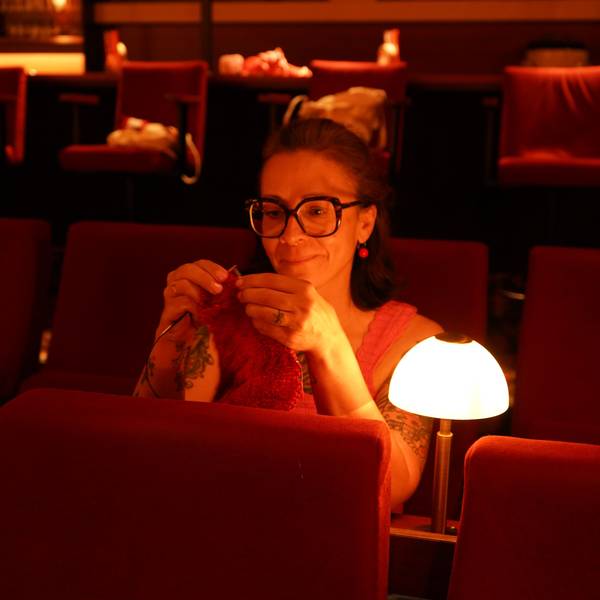 Das Foto zeigt eine strickende Frau im Kino.