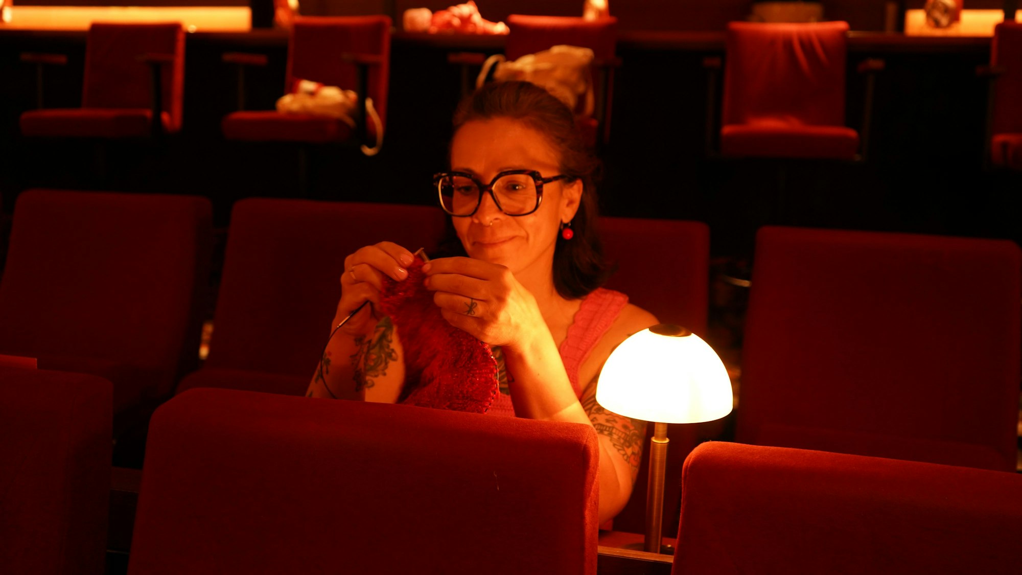 Das Foto zeigt eine strickende Frau im Kino.