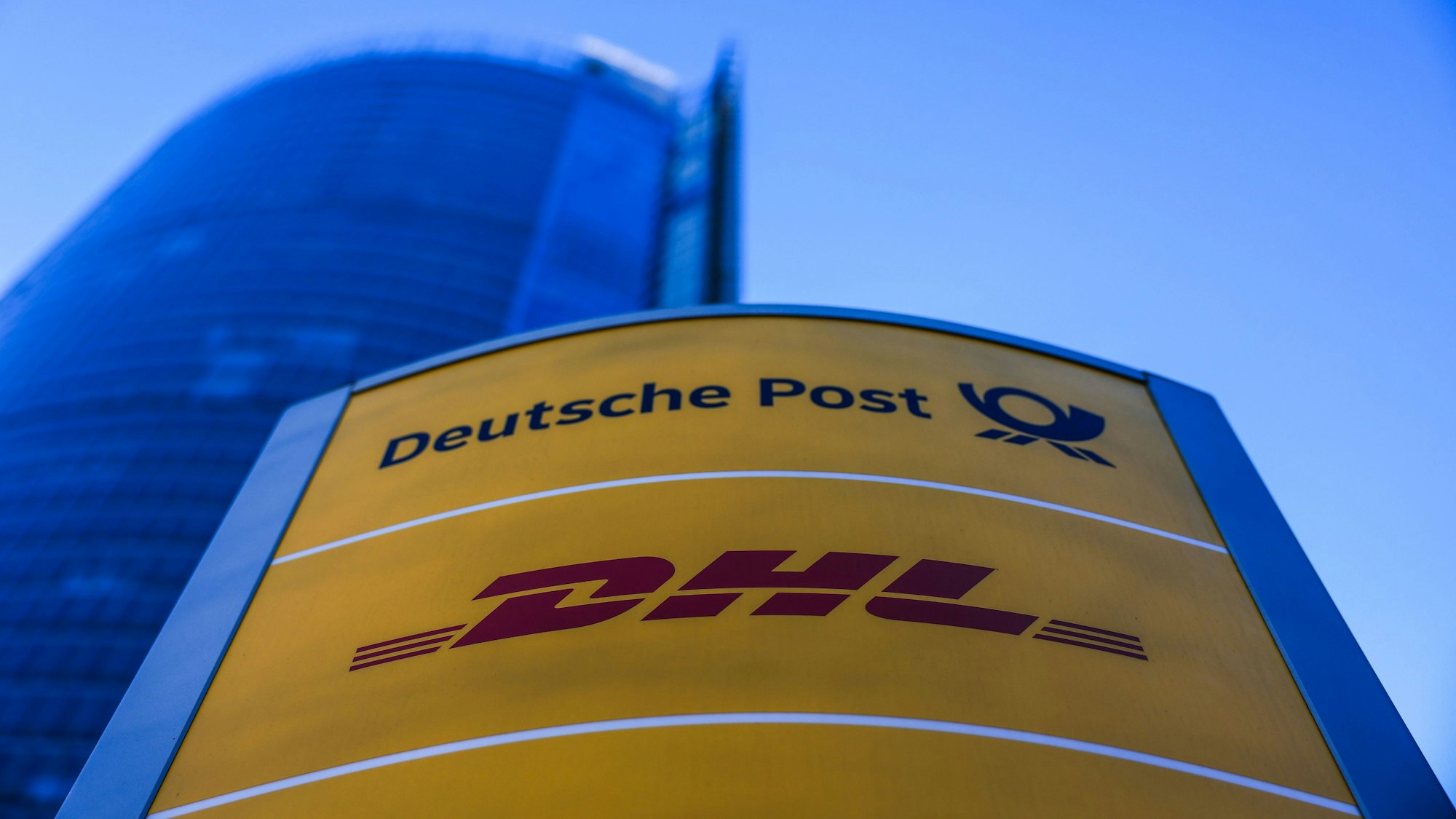 Die Logos von DHL und Deutsche Post stehen vor dem Posttower in Bonn.