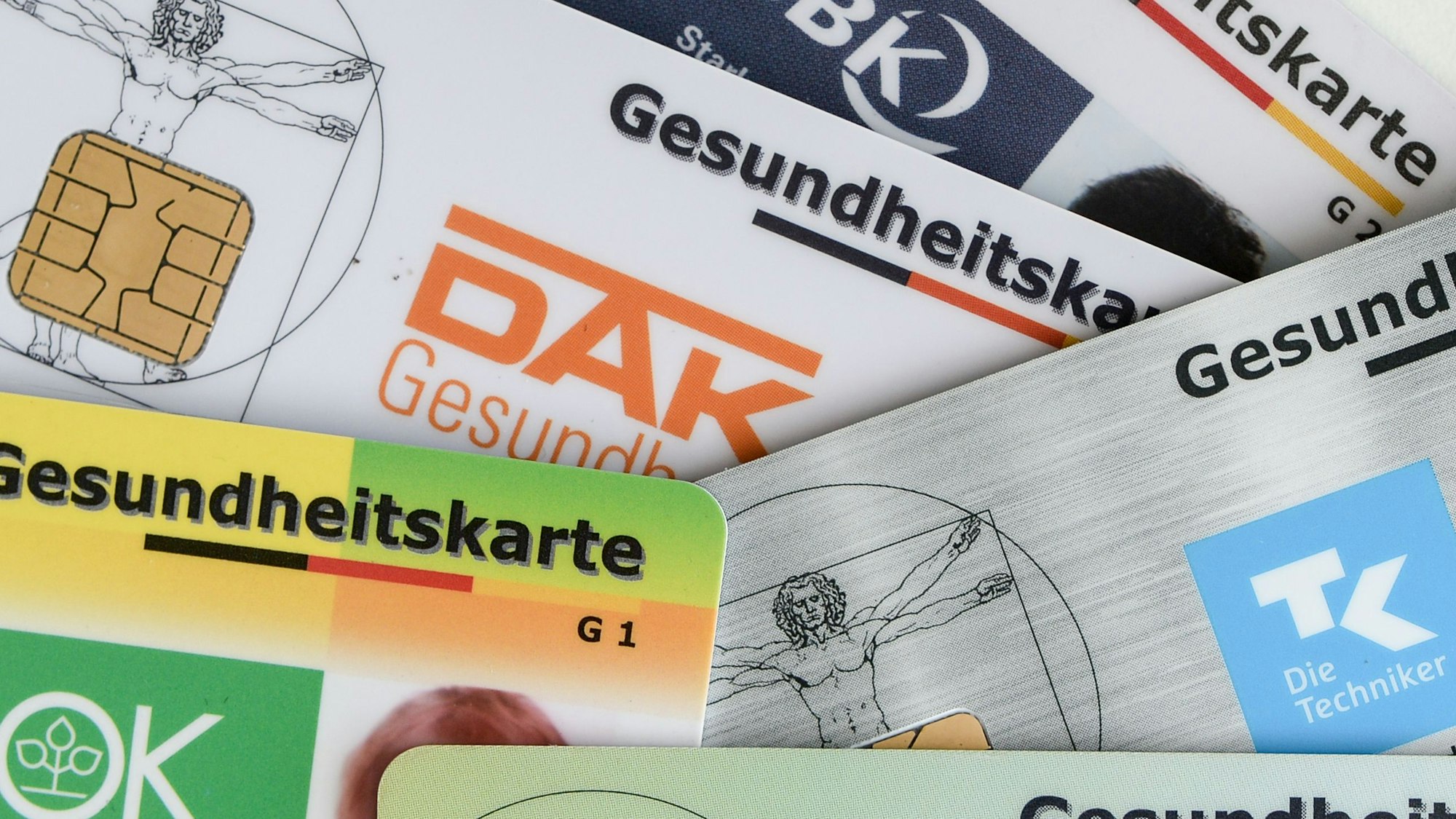 Gesundheitskarten verschiedener Krankenkassen liegen auf einem Tisch.