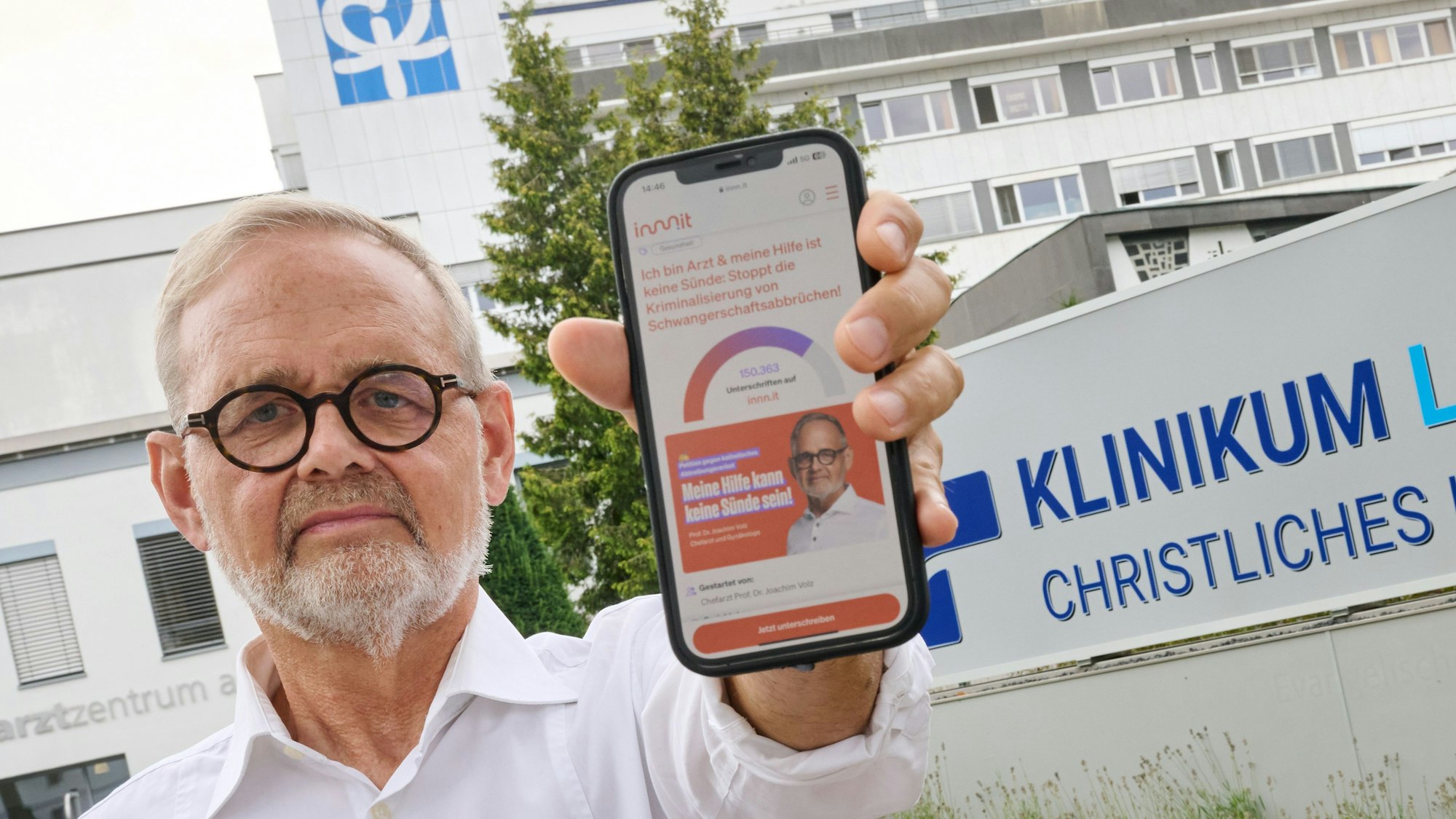 Der Gynäkologe Joachim Volz zeigt vor dem Klinikum Lippstadt - Christliches Krankenhaus sein Mobiltelefon, auf dem seine Online-Petition zu sehen ist. Nach der Fusion zweier Krankenhäuser darf der Gynäkologe gemäß einer neuen Dienstanweisung des katholischen Trägers keine Schwangerschaftsabbrüche mehr durchführen. Dagegen wendet sich der langjährige Chefarzt mit einer Klage.