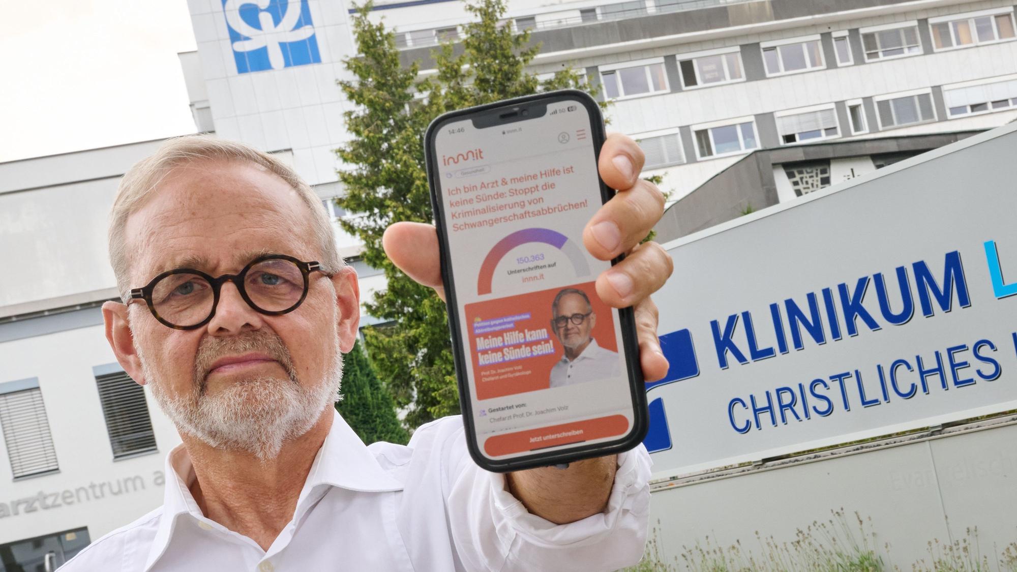Der Gynäkologe Joachim Volz zeigt vor dem Klinikum Lippstadt - Christliches Krankenhaus sein Mobiltelefon, auf dem seine Online-Petition zu sehen ist. Nach der Fusion zweier Krankenhäuser darf der Gynäkologe gemäß einer neuen Dienstanweisung des katholischen Trägers keine Schwangerschaftsabbrüche mehr durchführen. Dagegen wendet sich der langjährige Chefarzt mit einer Klage.