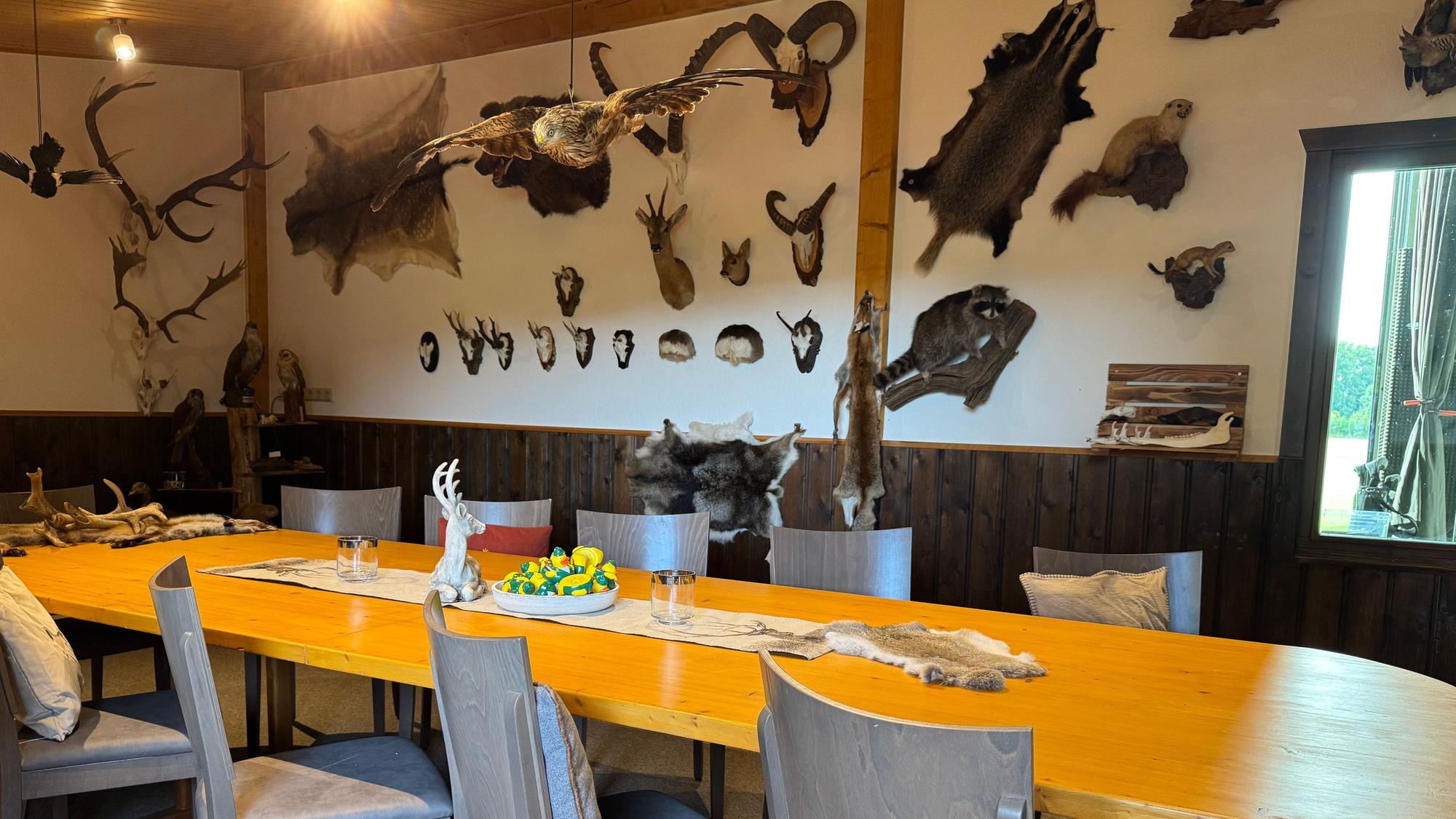 Das Bild zeigt einen Raum, ein langer Tisch in der Mitte, an den Wänden zahlreiche Trophäen erlegter Tiere.