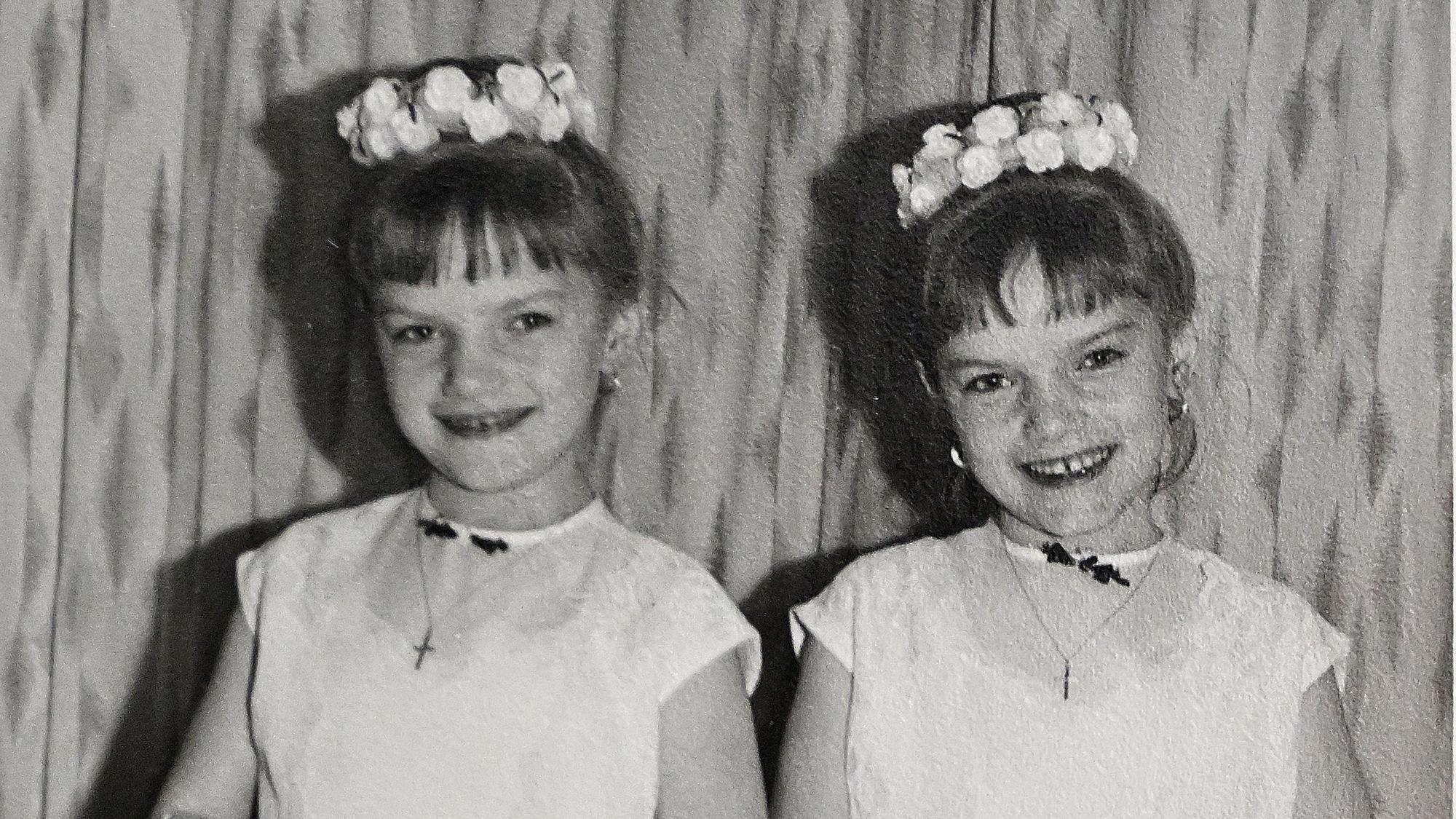 Auf einem Kinderfoto tragen die Zwillinge jeweils einen Blumenkranz und ein weißes Kleid.