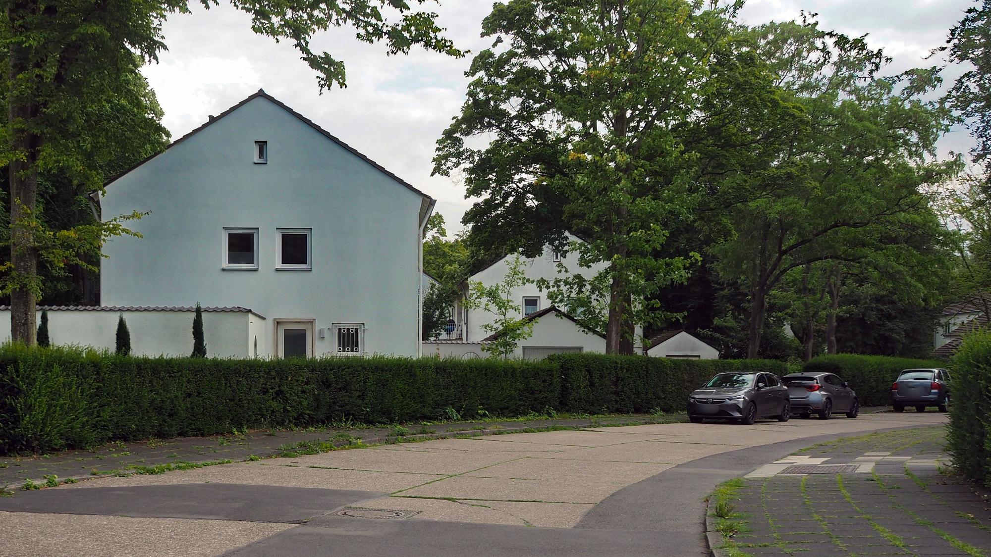 An einer Straße sind mehrere weiße Häuser mit drei Etagen zu sehen.