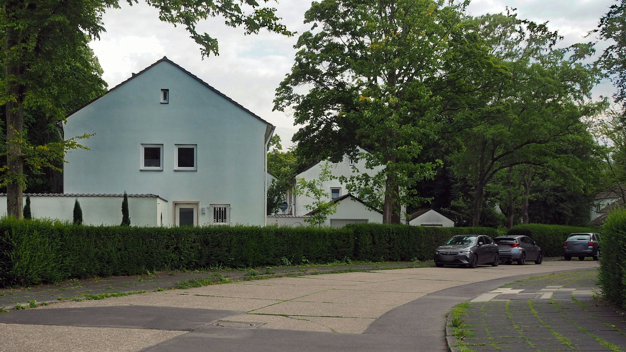 An einer Straße sind mehrere weiße Häuser mit drei Etagen zu sehen.