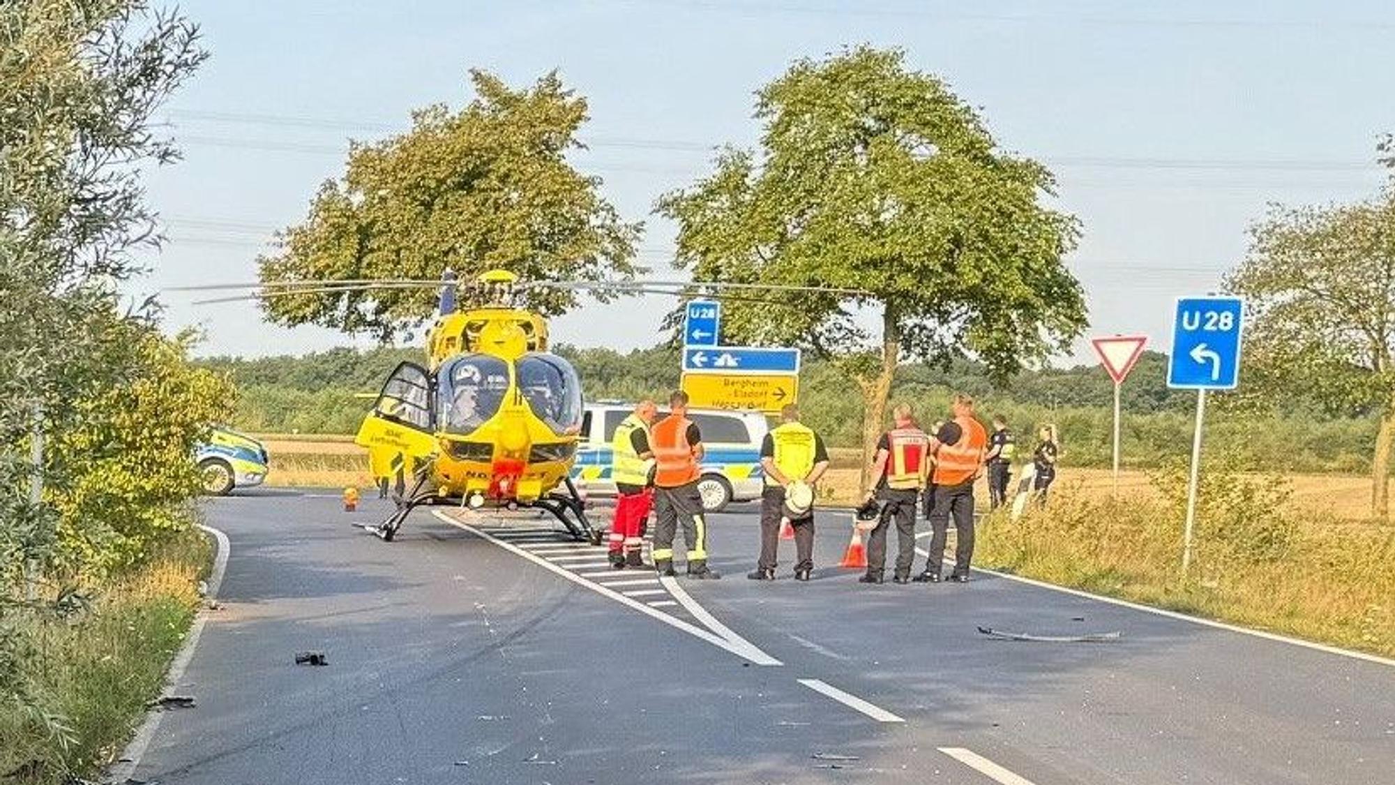 Das Bild zeigt eine Straßeneinmündung mit Einsatzkräften der Feuerwehr und einem Rettungshubschrauber