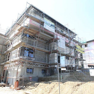 Ein Haus in Much wird gebaut und ist von allen Seiten von einem Gerüst umschlossen.