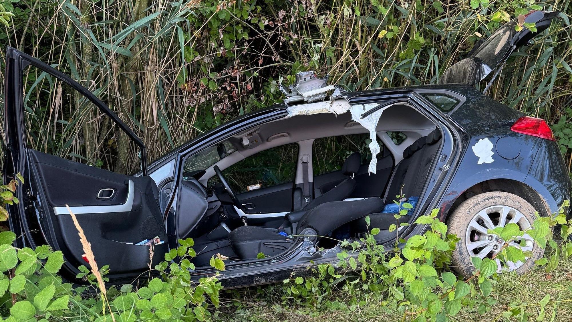 Das Bild zeigt einen Kleinwagen in einem Straßengraben.