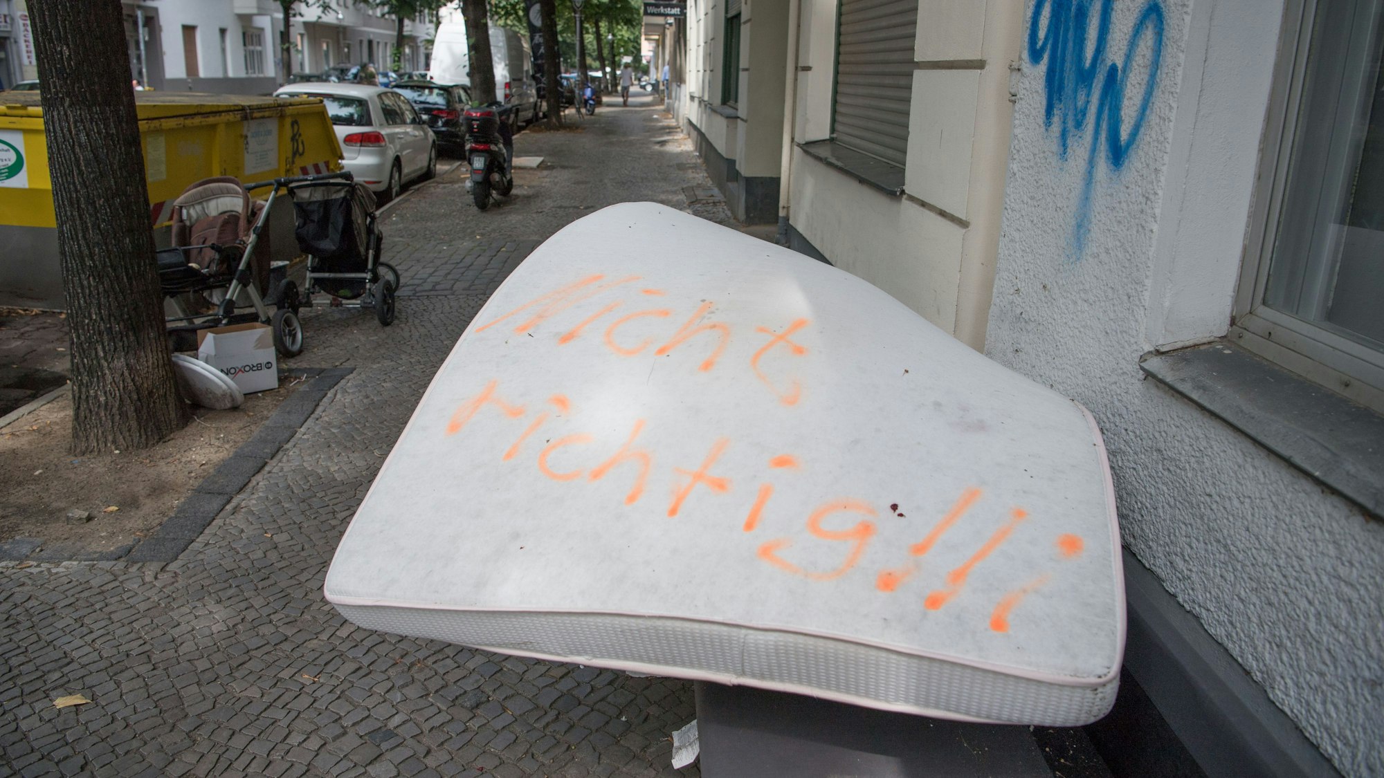 Eine illegal entsorgte Matratze liegt auf einem Gehweg, darauf wurden die Worte „Nicht richtig!!“ gesprüht.