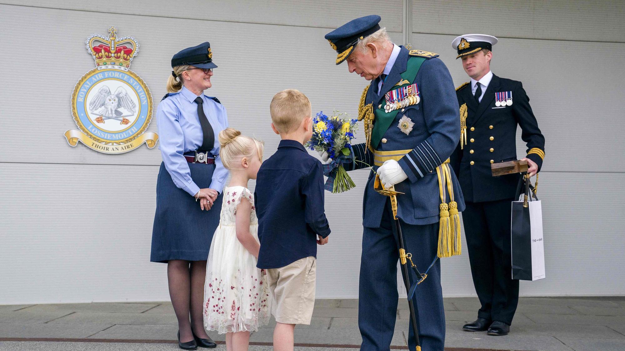 König Charles III. nimmt bei seinem Besuch der Royal Air Force in Lossiemouth ein Geschenk zweier Kinder entgegen.