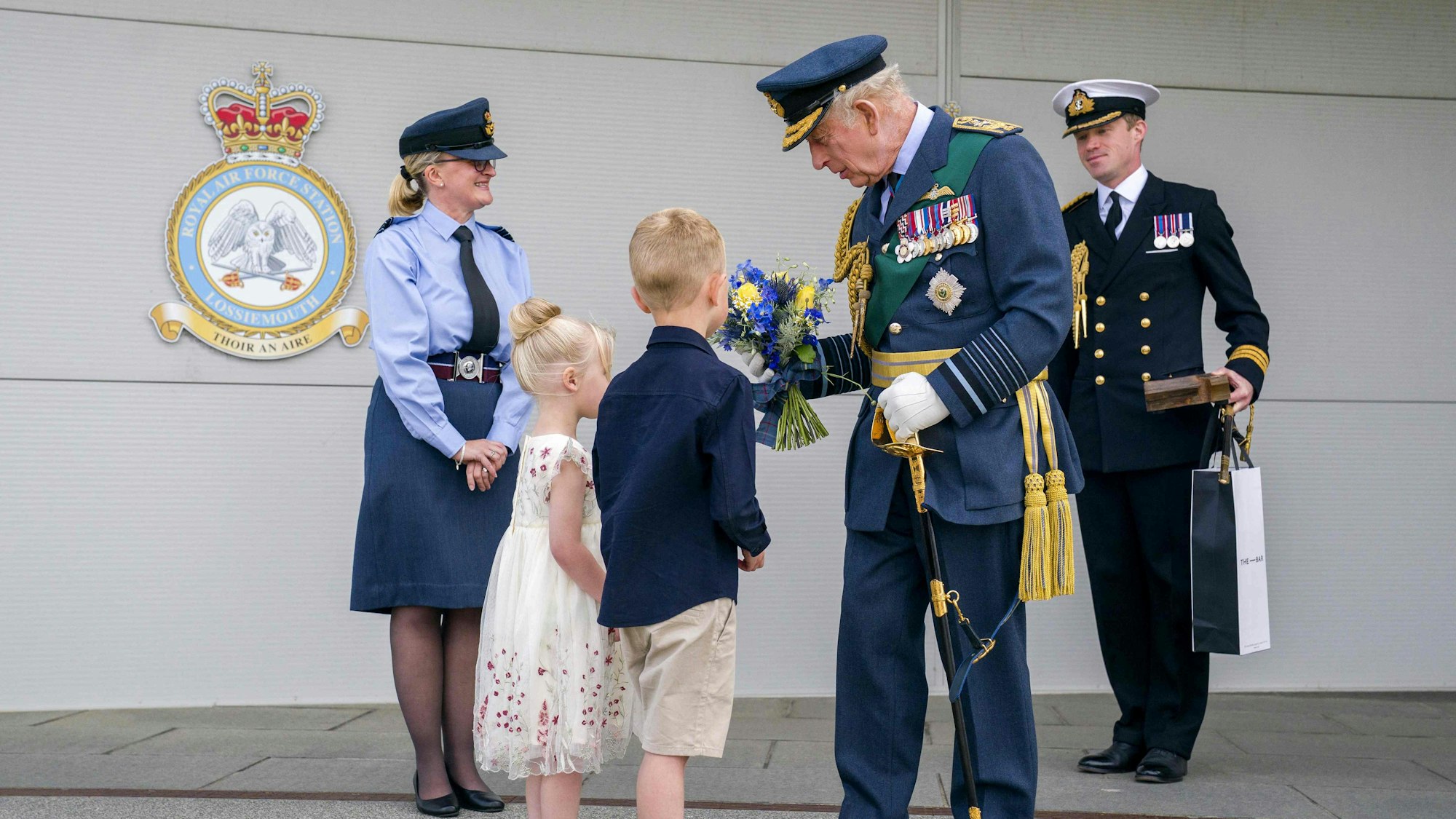 König Charles III. nimmt bei seinem Besuch der Royal Air Force in Lossiemouth ein Geschenk zweier Kinder entgegen.