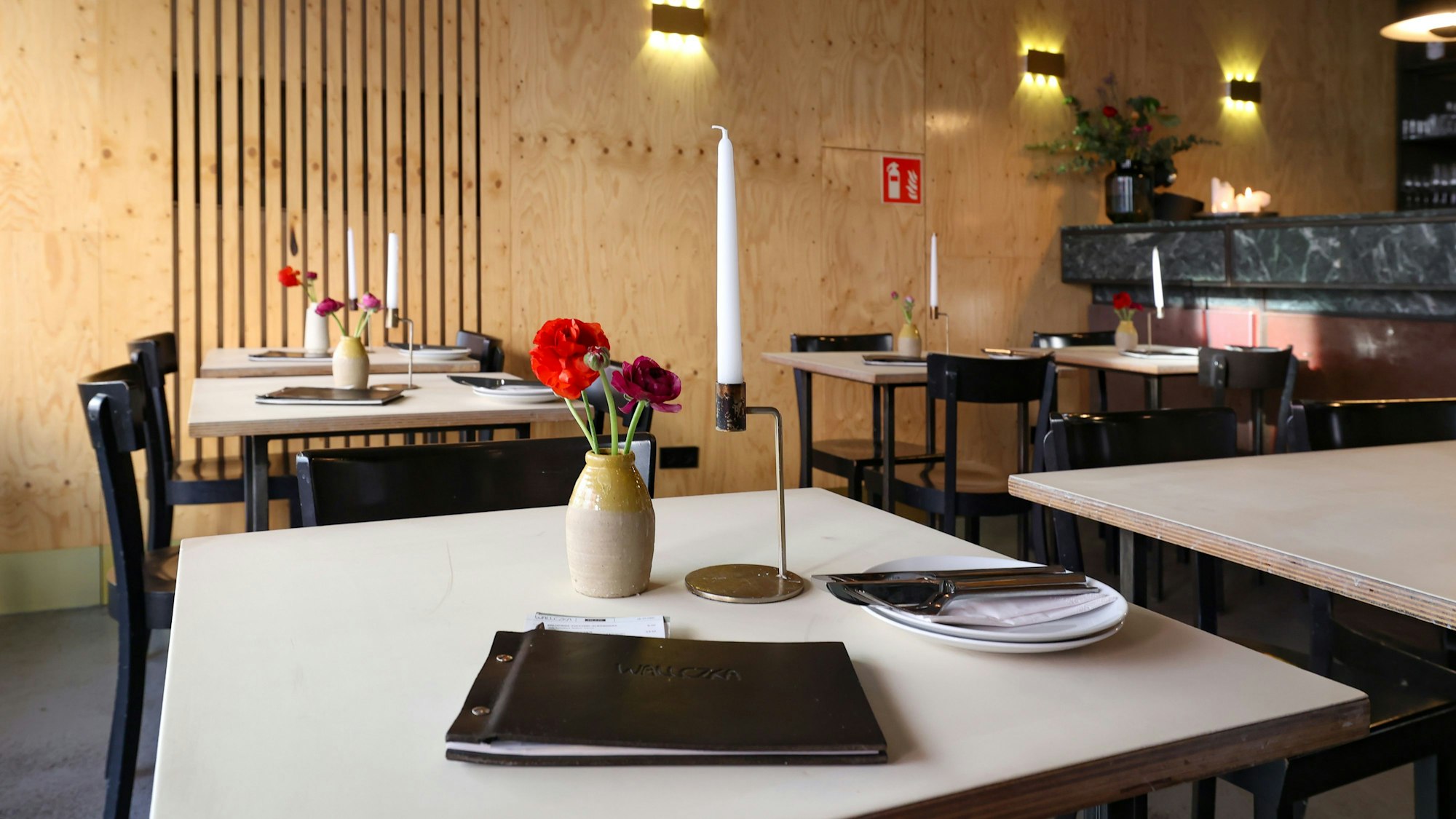 Das Restaurant Wallczka in Ehrenfeld mit Tischen und Stühlen, auf dem Tisch stehen Blumen, es liegt eine Speisekarte darauf. (Archivbild 2024)