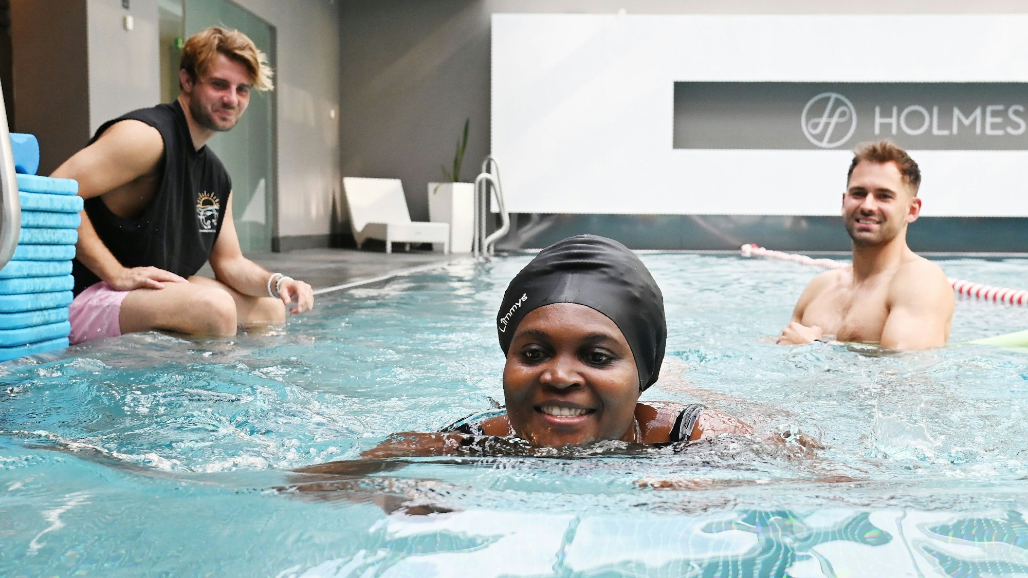 05.08.2025 Köln. Bei der Schwimmschule Otterbuddies lernen auch Erwachsene, wie man sicher und ressourcenschonend schwimmt - das ist besonders in Notlagen wichtig. Wir besuchen eine Einheit. Yannick Hilgers ( mit Shirt ) und Fabian Thorwesten unterrichten Cindy. Foto: Alexander Schwaiger