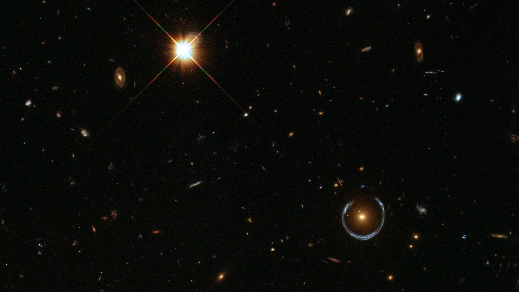 Das „Kosmische Hufeisen“: Die Gravitationskraft einer massereichen Galaxie verzerrt das Licht einer weiter entfernten, blauen Galaxie zu einem nahezu vollständigen Einstein-Ring.