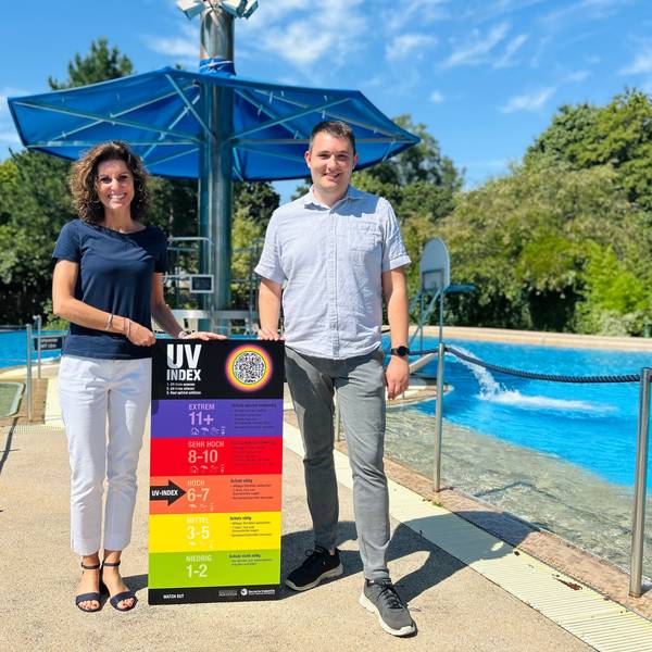 Betriebsleiterin des Sportpark Leverkusen, Nelly Schreiner (v.l.), und Badleiter des CaLevornia, Sebastian Frohn präsentieren das neue UV-Index-Schild am CaLevornia.