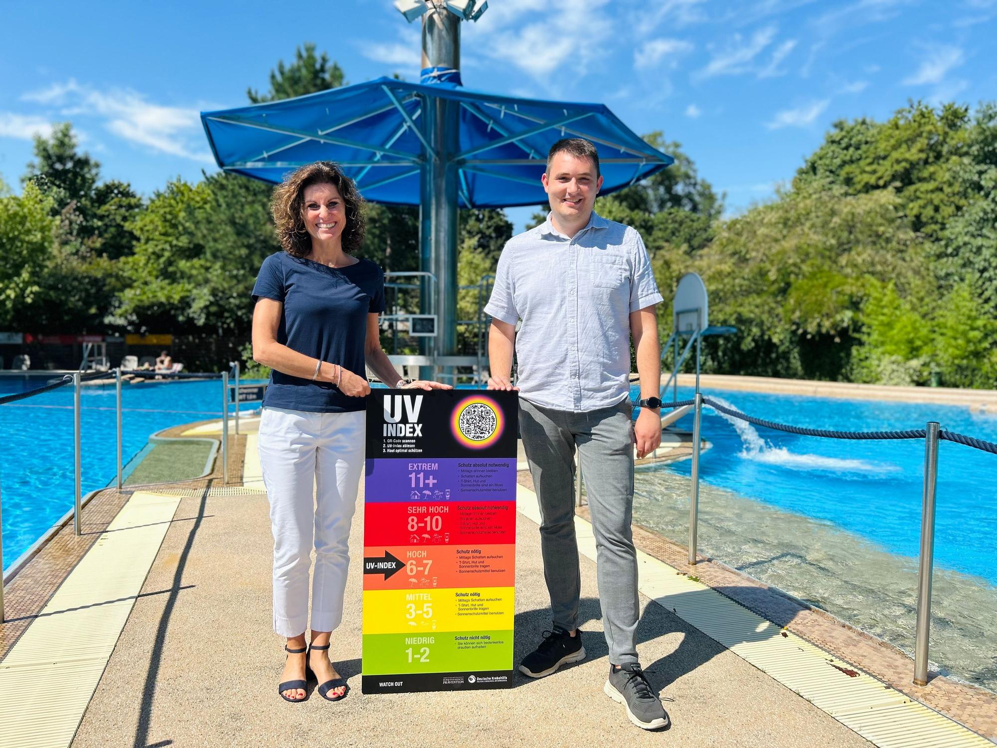 Betriebsleiterin des Sportpark Leverkusen, Nelly Schreiner (v.l.), und Badleiter des CaLevornia, Sebastian Frohn präsentieren das neue UV-Index-Schild am CaLevornia.