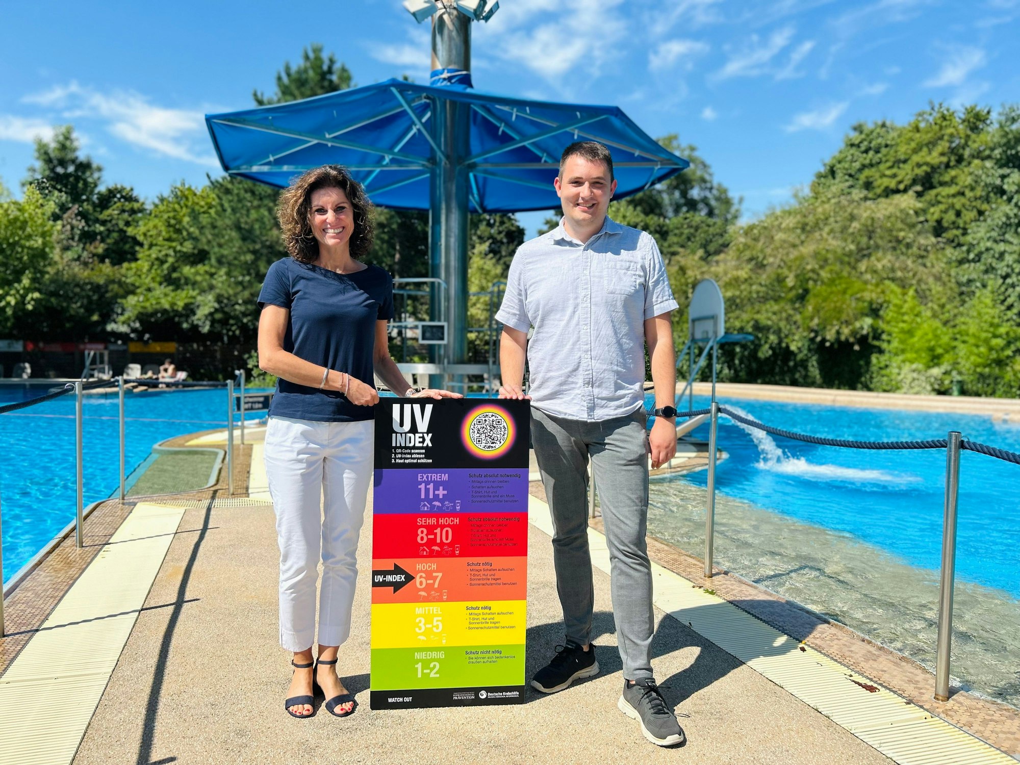 Betriebsleiterin des Sportpark Leverkusen, Nelly Schreiner (v.l.), und Badleiter des CaLevornia, Sebastian Frohn präsentieren das neue UV-Index-Schild am CaLevornia.