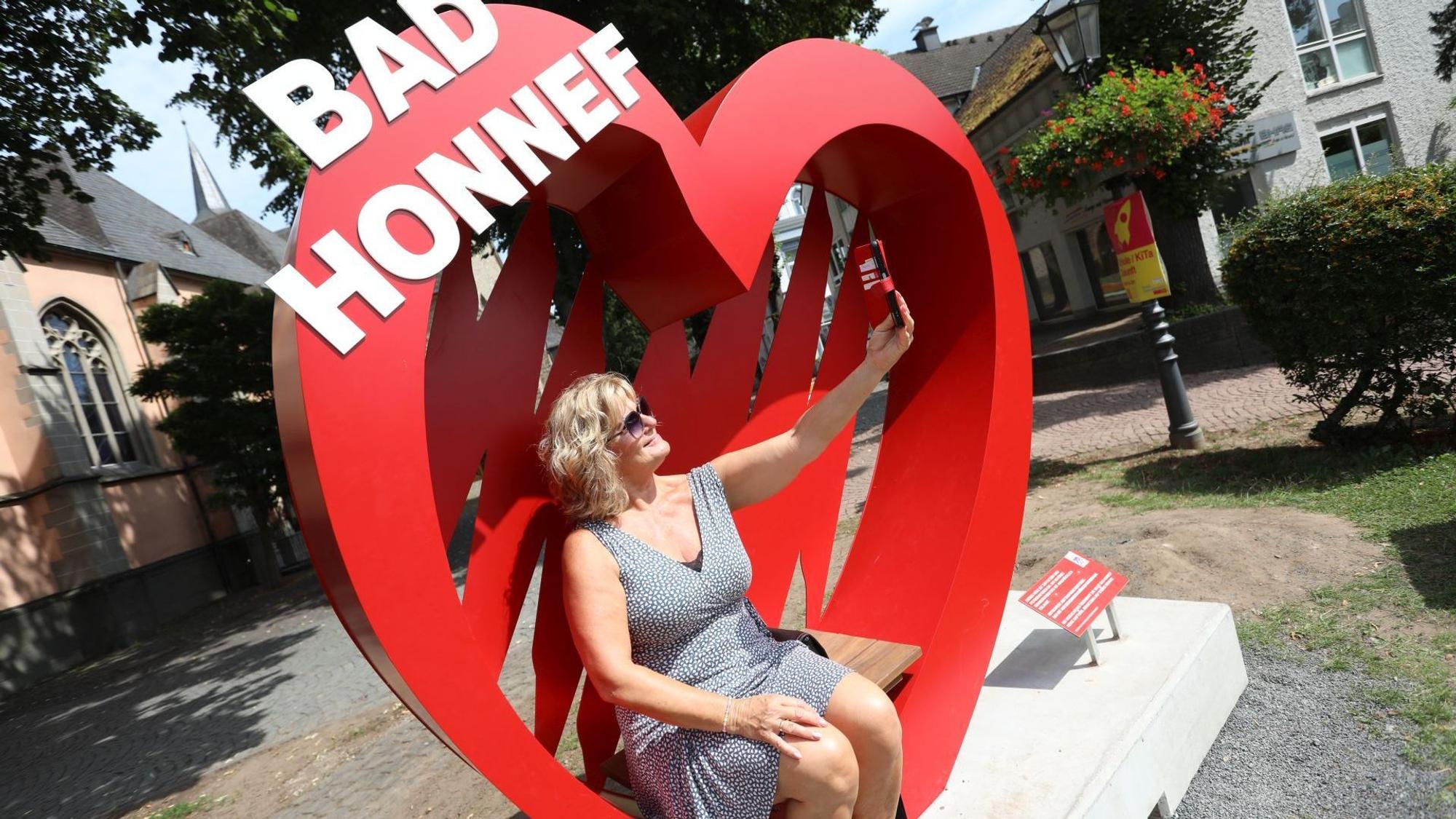 Eine Frau macht ein Selfie in einem großen roten Herz mit dem Schriftzug Bad Honnef.