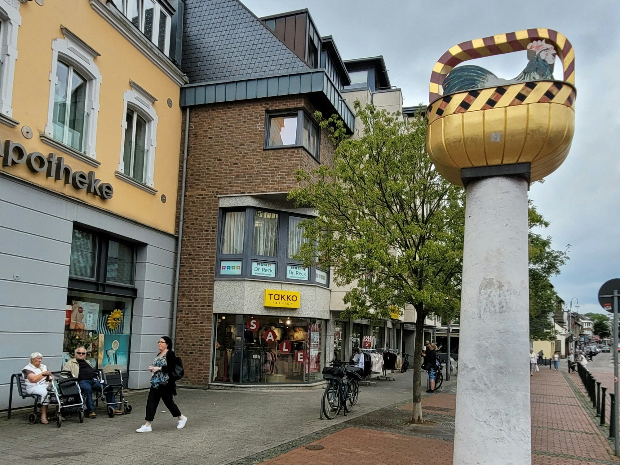 Ein Hahn in einem goldglänzenden Korb thront auf einer Säule.
