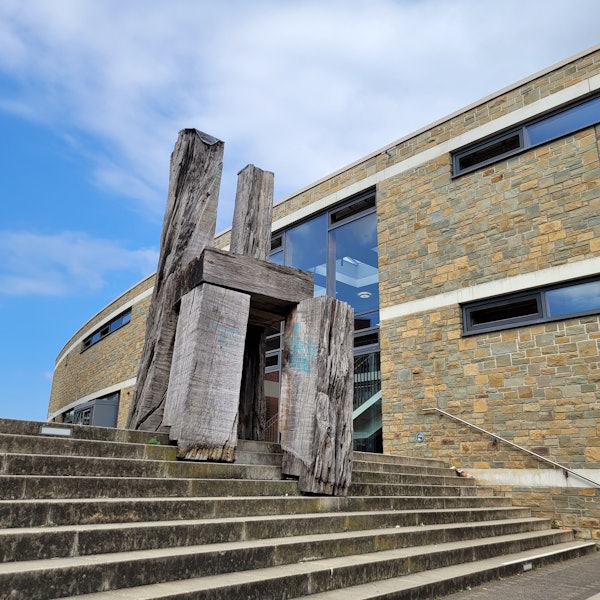 Eine riesige Skulpur aus Holz auf einer Treppe, sie hat die Form eines Stuhls.