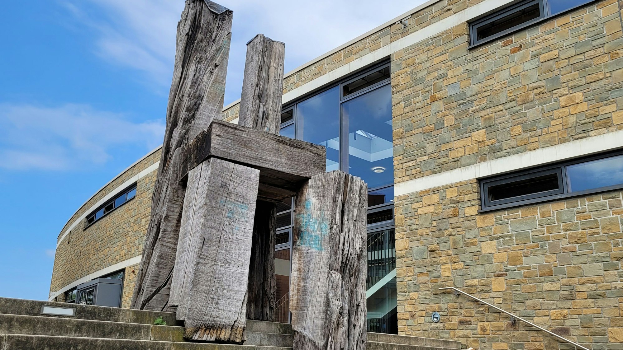 Eine riesige Skulpur aus Holz auf einer Treppe, sie hat die Form eines Stuhls.