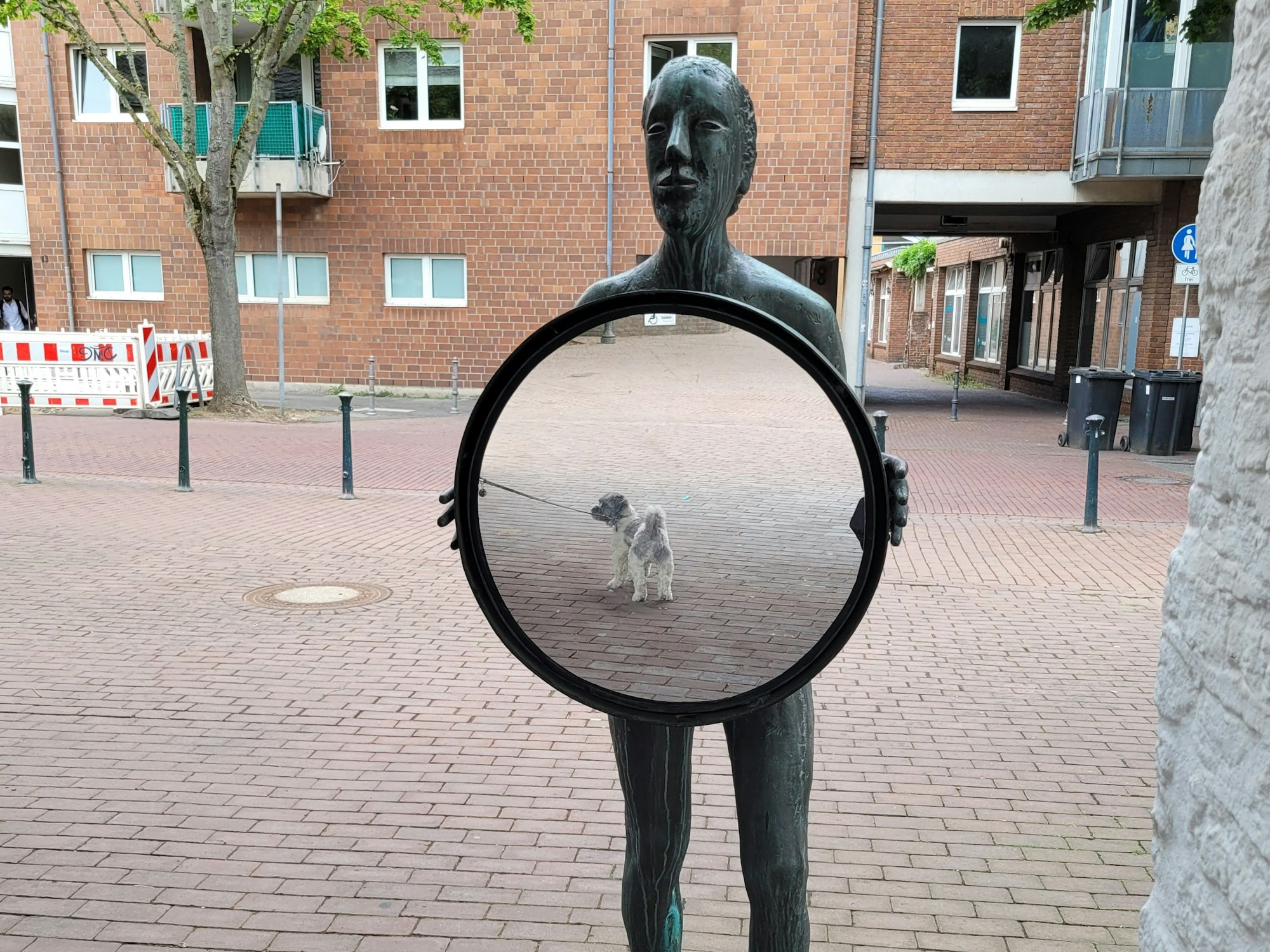 Eine Figur, sie hält einen Spiegel in den Händen.