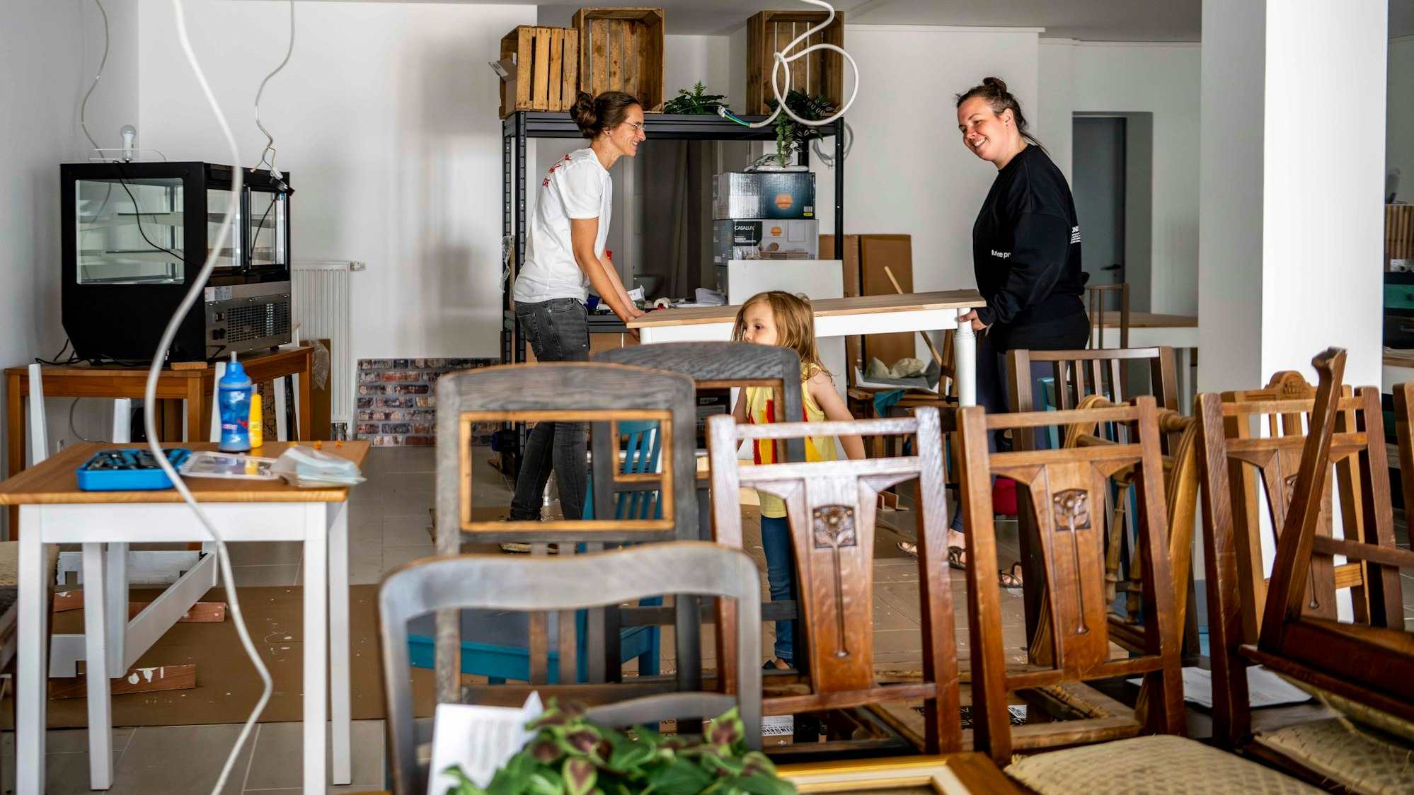 Das Bild zeigt Andrea Pick, die mit ihrer Frau Julia einen Tisch trägt.