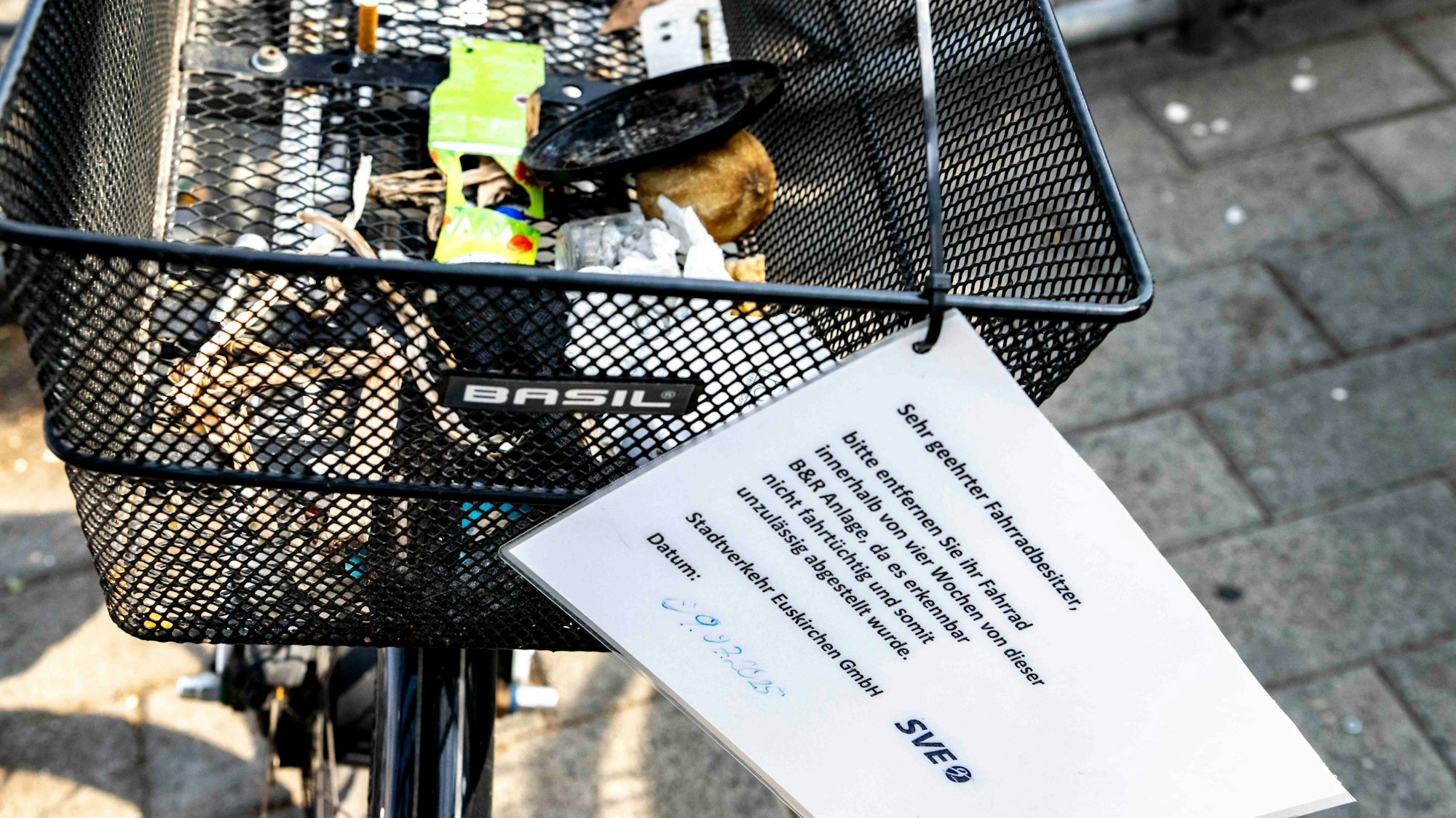 Das Bild zeigt einen vermüllten Korb an einem Fahrrad. Die SVE hat ein Schild angebracht. Der Besitzer wird aufgefordert, dass Rad zu entfernen.