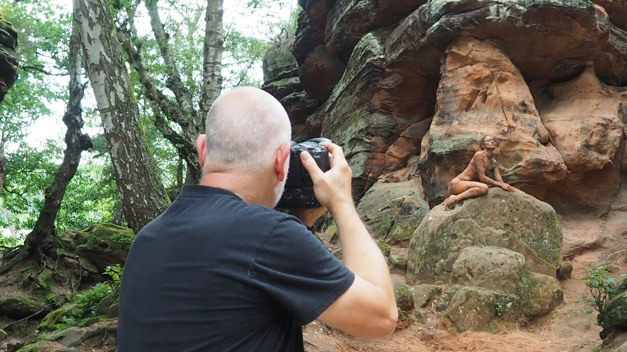 Das Model kauert auf einem Felsbrocken, im Vordergrund ist der Fotograf von hinten zu sehen.