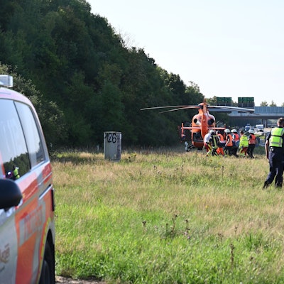 Das Bild zeigt Einsatzkräfte der Feuerwehr, die einen schwerverletzten Mann in den Rettungshubschrauber tragen.