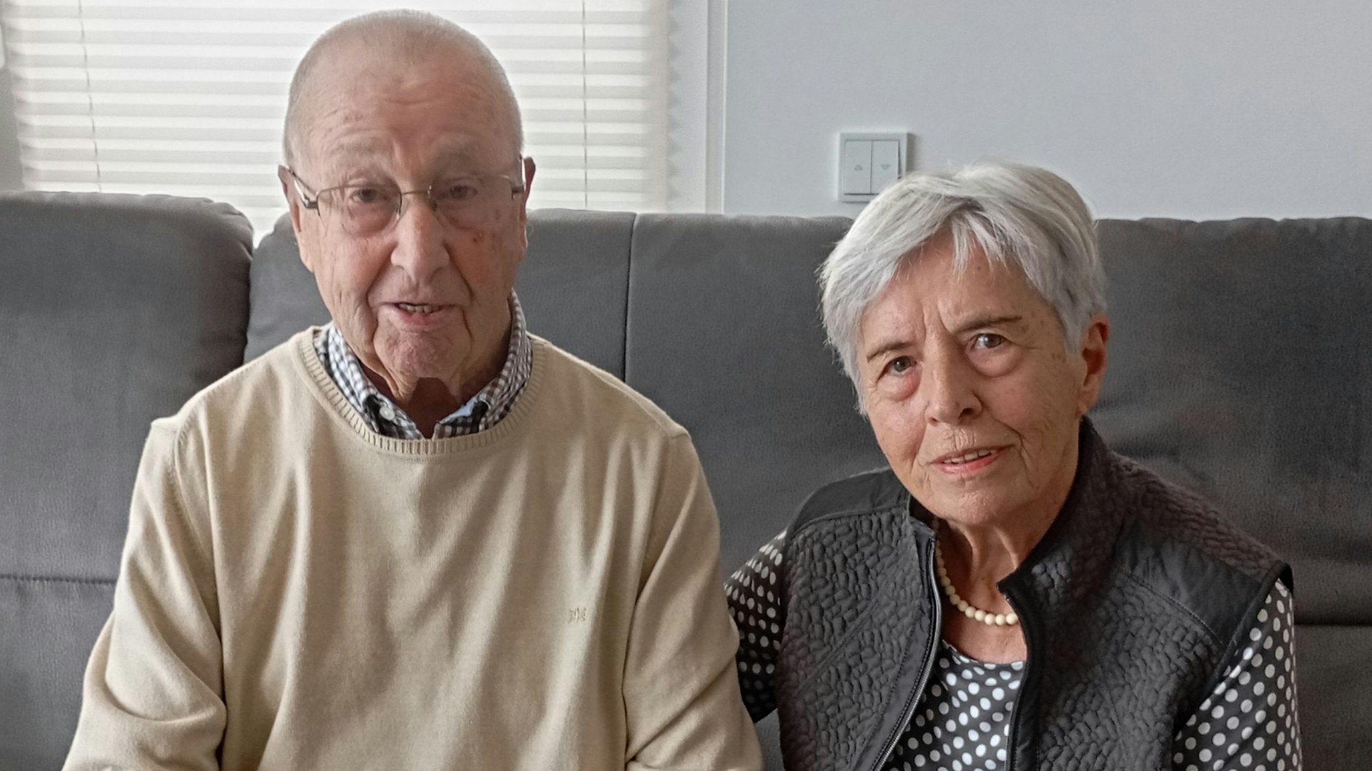 Die beiden sitzen auf einem Sofa. Ingeborg Schulte legt den Arm auf den Rücken ihres Mannes .