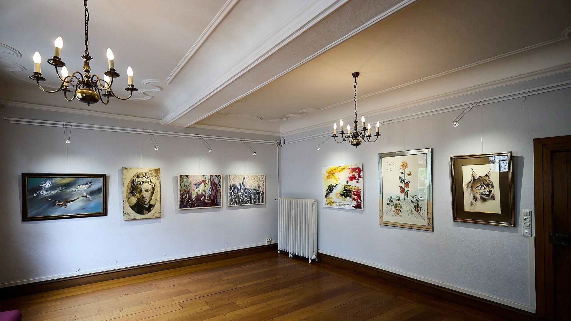 Blick in einen Ausstellungsraum mit mehreren Kunstwerken an den Wänden.
