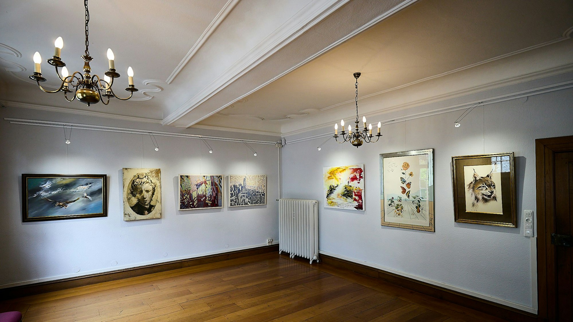 Blick in einen Ausstellungsraum mit mehreren Kunstwerken an den Wänden.