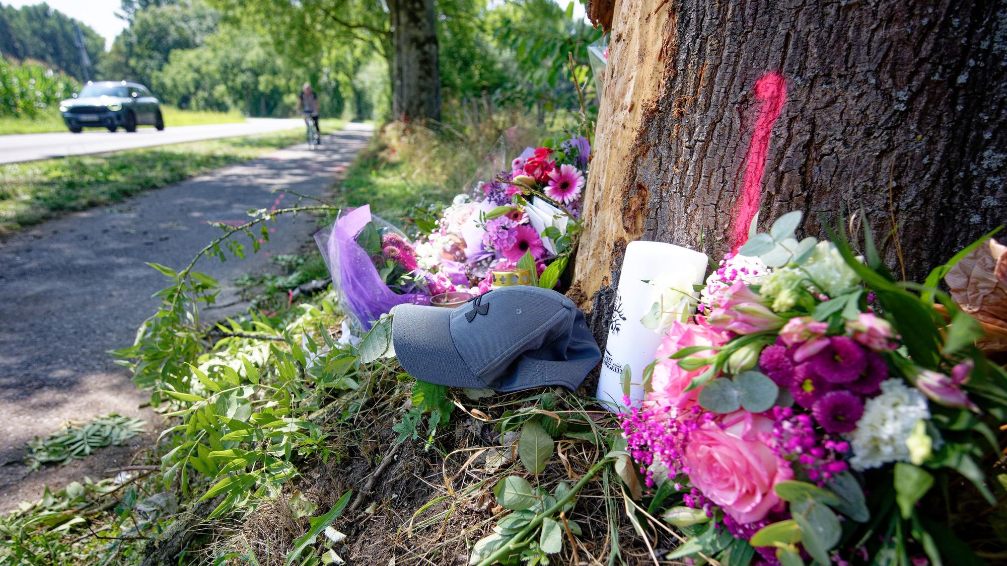 10.08.2025, Nordrhein-Westfalen, Monheim: Blumen, Kerzen und eine Mütze liegen an einer Unfallstelle zwischen Monheim und Düsseldorf. Bei dem Unfall verstarben ein 15-Jährige und eine 17-Jährige. Drei weitere Insassen den Unfallfahrzeuges wurden schwer verletzt. Foto: Henning Kaiser/dpa +++ dpa-Bildfunk +++