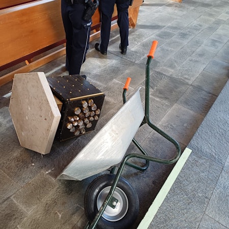 Neben einer umgekippten Schubkarre liegt ein Tabernakel auf dem Boden.