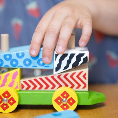 Ein Kind spielt mit einer Holzeisenbahn. (Archivbild)