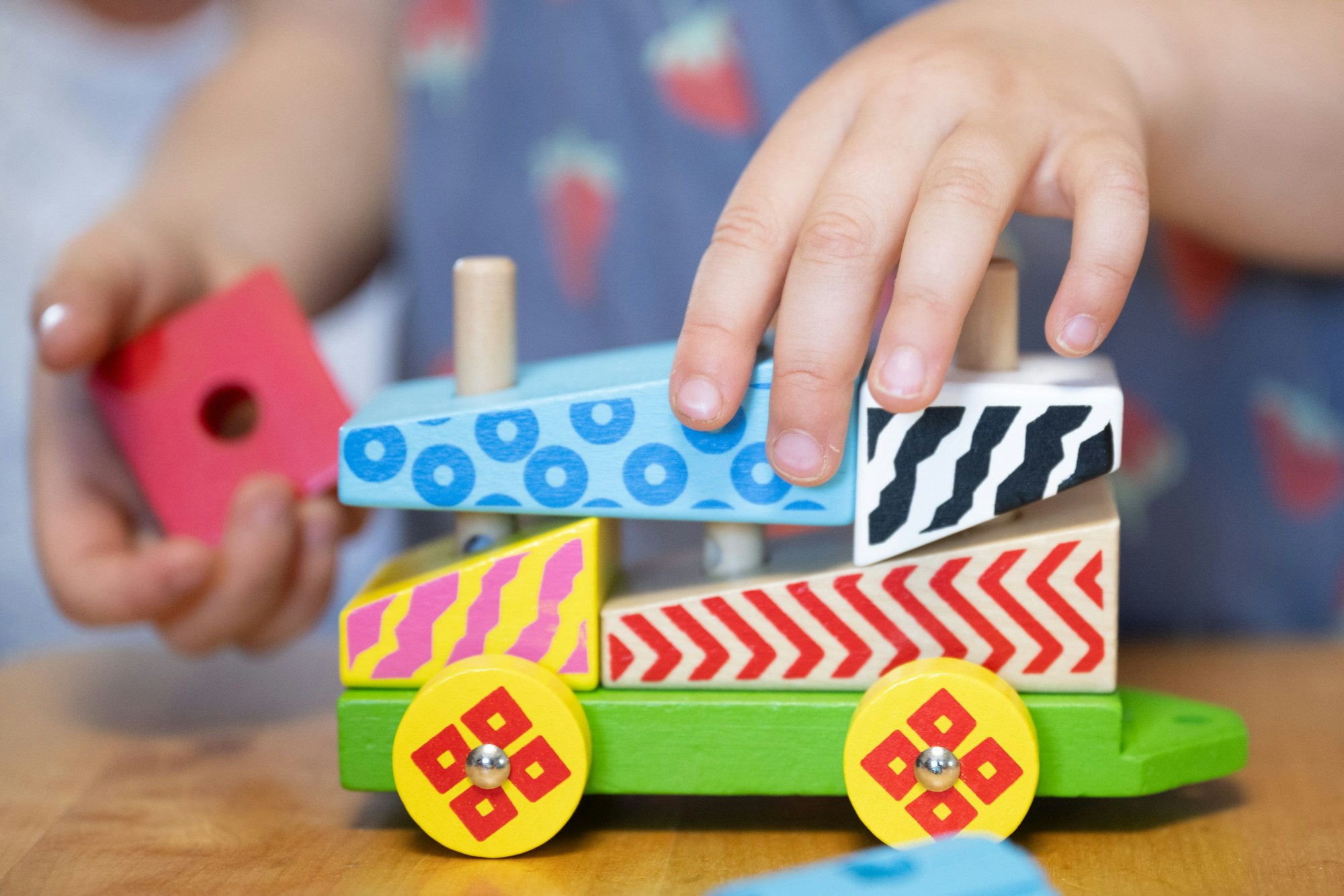 Ein Kind spielt mit einer Holzeisenbahn. (Archivbild)