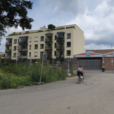 Bauzäune stehen links und rechts von einer Straßen-Einfahrt.
