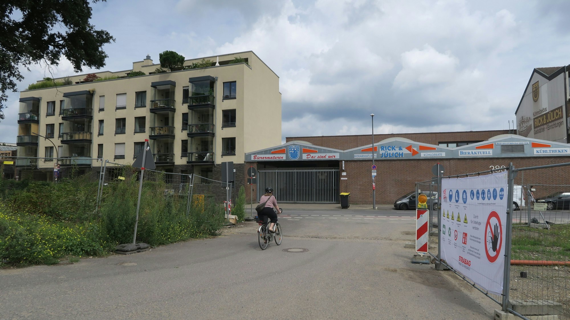 Bauzäune stehen links und rechts von einer Straßen-Einfahrt.