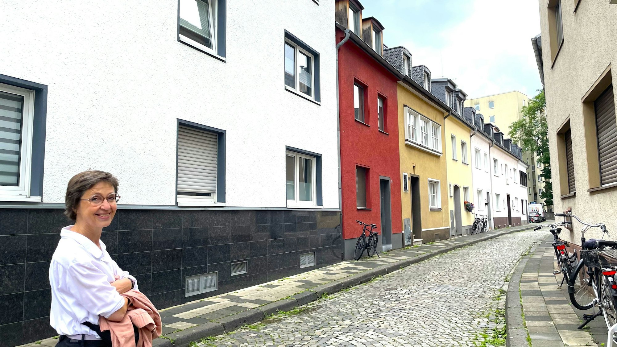 Eine Frau schaut in die Kamera, während sie durch eine schmale Straße geht.