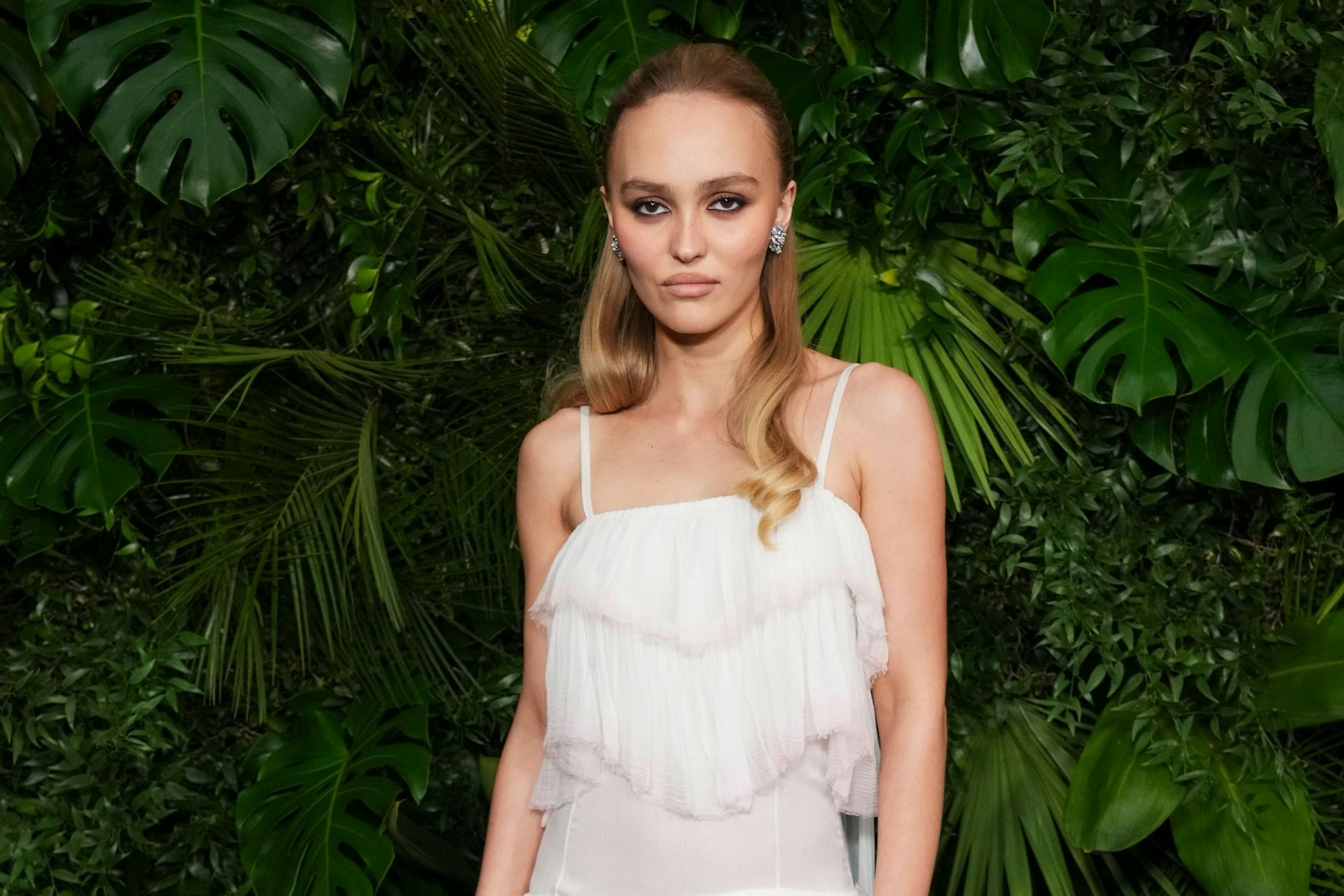 Schauspielerin Lily-Rose Depp schaut in typischer roter Teppich-Pose mit kühler Miene in die Kamera. (Archivbild)