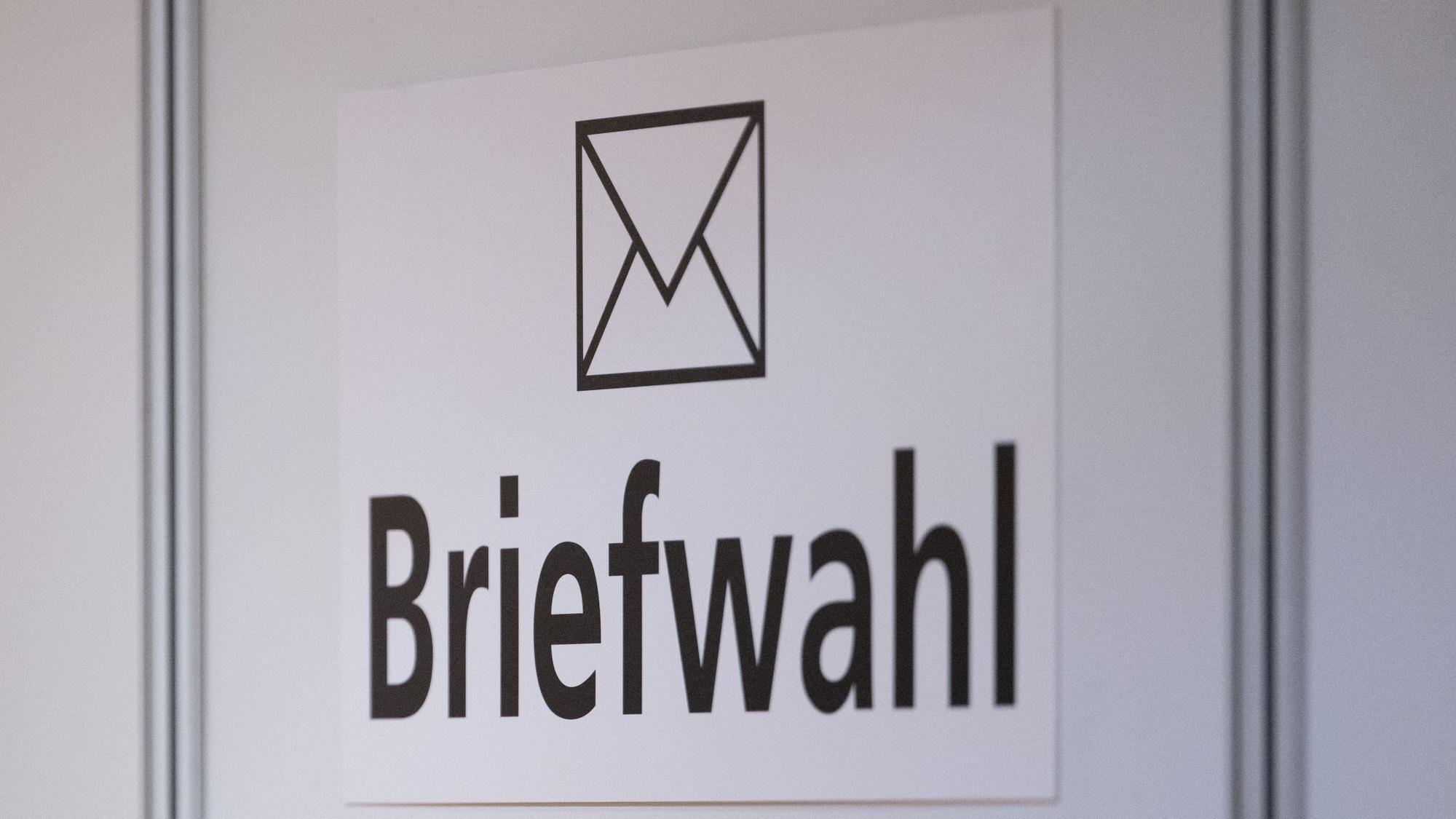 Das Wort Briefwahl ist im Foyer des Rathauses an einer Wand zu sehen.