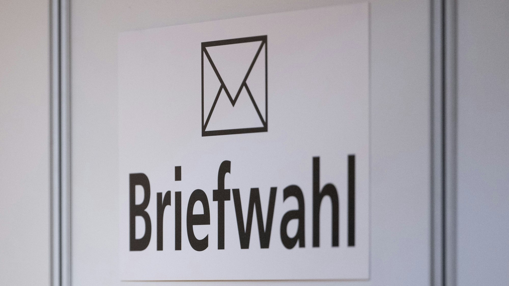 Das Wort Briefwahl ist im Foyer des Rathauses an einer Wand zu sehen.