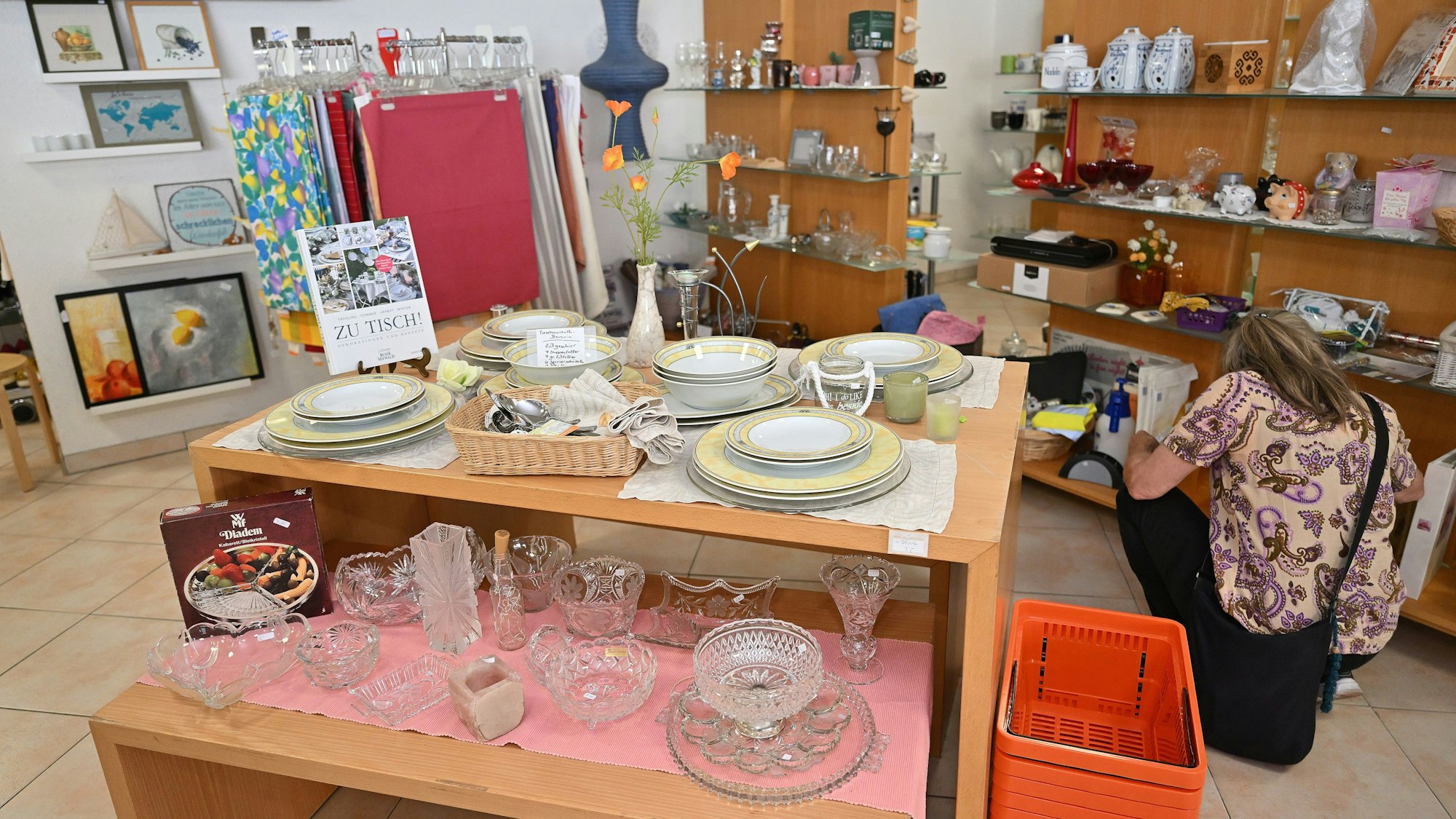 Eine Kundin hockt vor einem Regal mit Haushaltswaren.