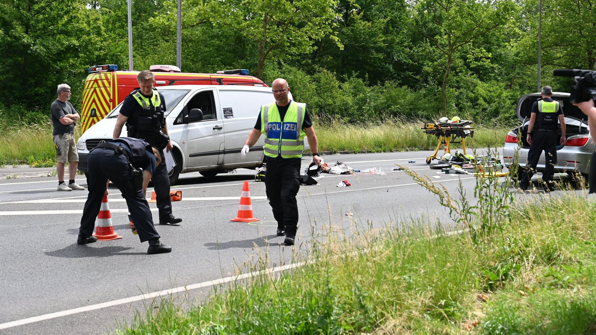 Zu sehen sind Polizisten, die Spuren an einer Unfallstelle auf einer Straße sichern.