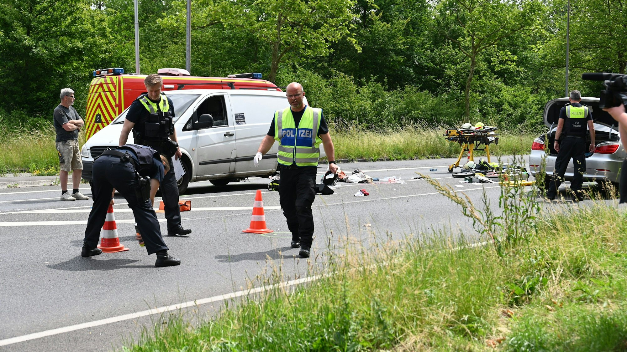 Zu sehen sind Polizisten, die Spuren an einer Unfallstelle auf einer Straße sichern.