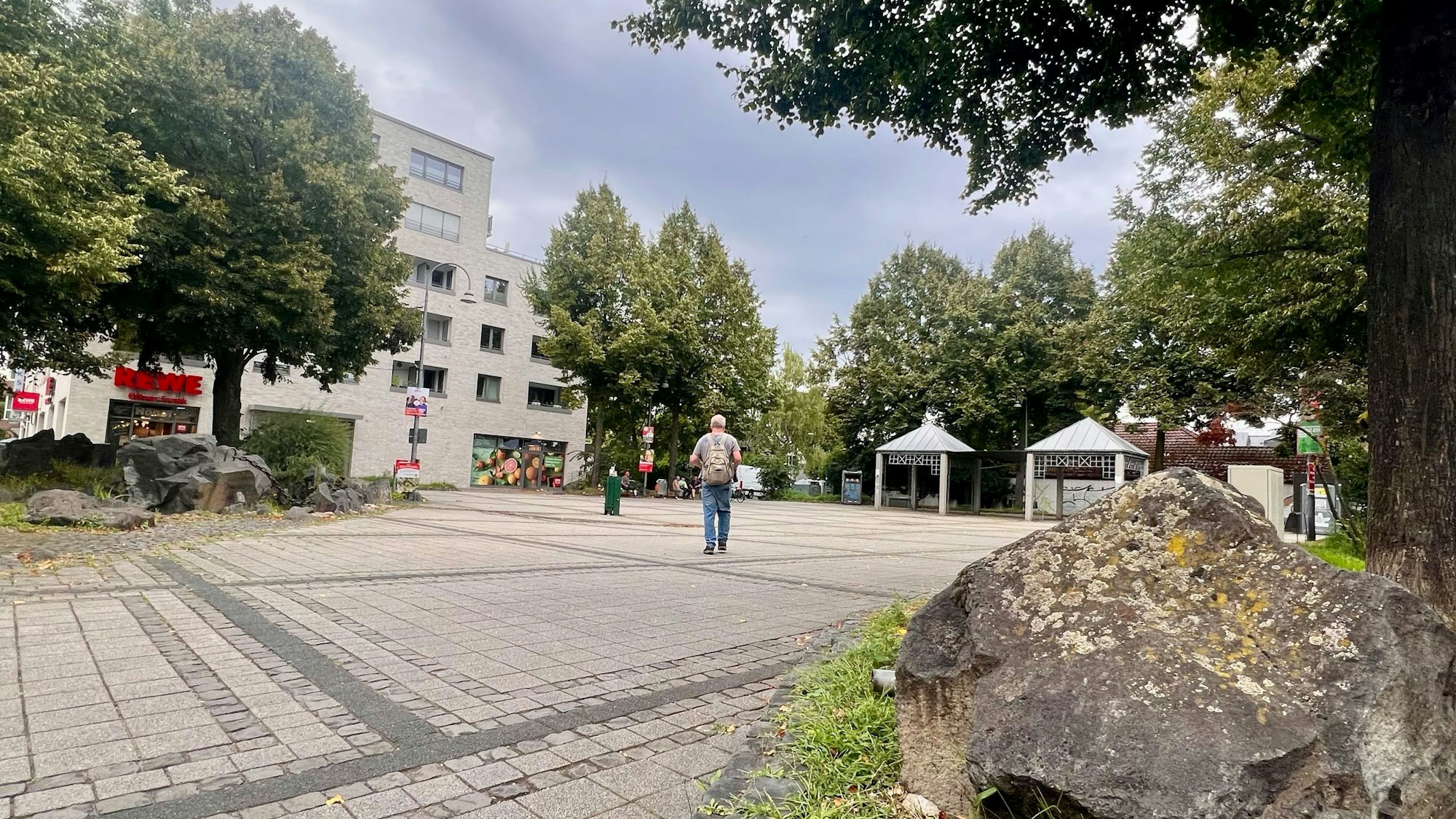 Ein freier asphaltierter Platz mit Bäumen drumherum ist zu sehen.