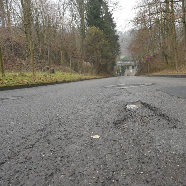 Die Dombach-Sander-Straße aus der Froschperspektive aufgenommen, zeigt die Schäden in der Fahrbahndecke.