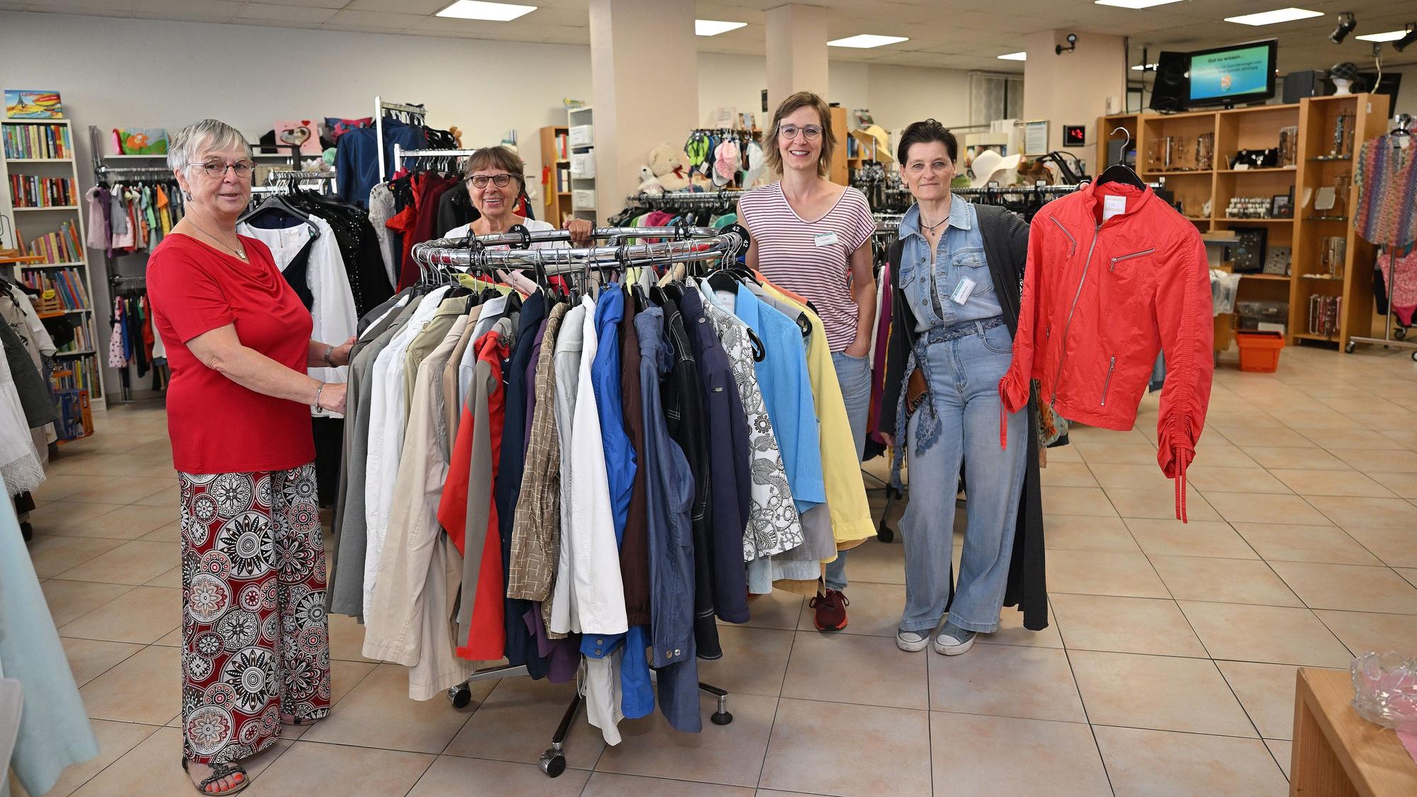 Vier Mitglieder des Adrashop-Teams stehen rund um eine Kleiderstange.